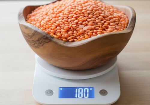 Lentilles corail crues pesées dans un bol sur une balance de cuisine
