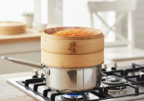 Lentilles corail dans un panier vapeur au-dessus d’une casserole